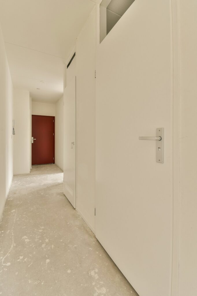 a hallway with white doors and a red door in