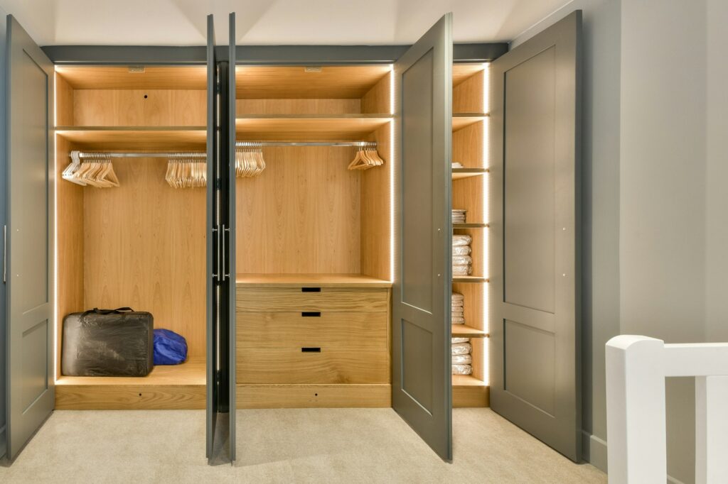 a walk in closet with wooden shelves and black doors